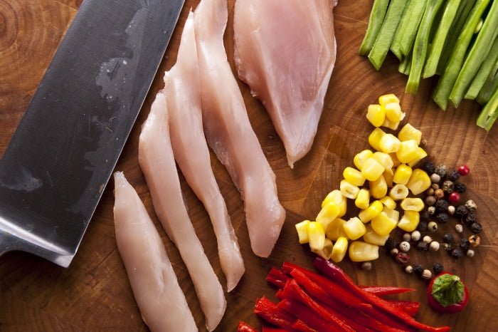 Preparing a chicken stir-fry with red and green peppers