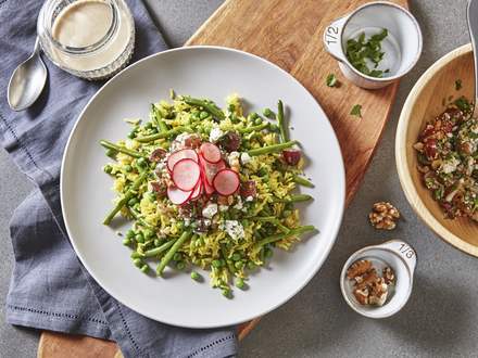 Basmati rice with green beans and peas topped with feta cheese and nuts